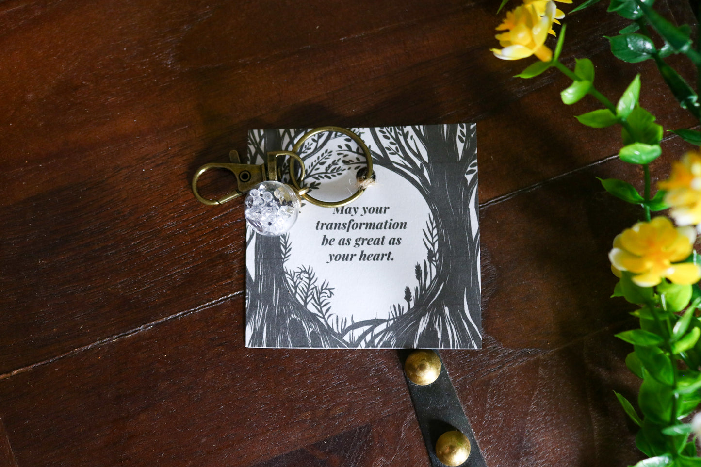 Keychain with motivational tag on a wooden surface with flowers