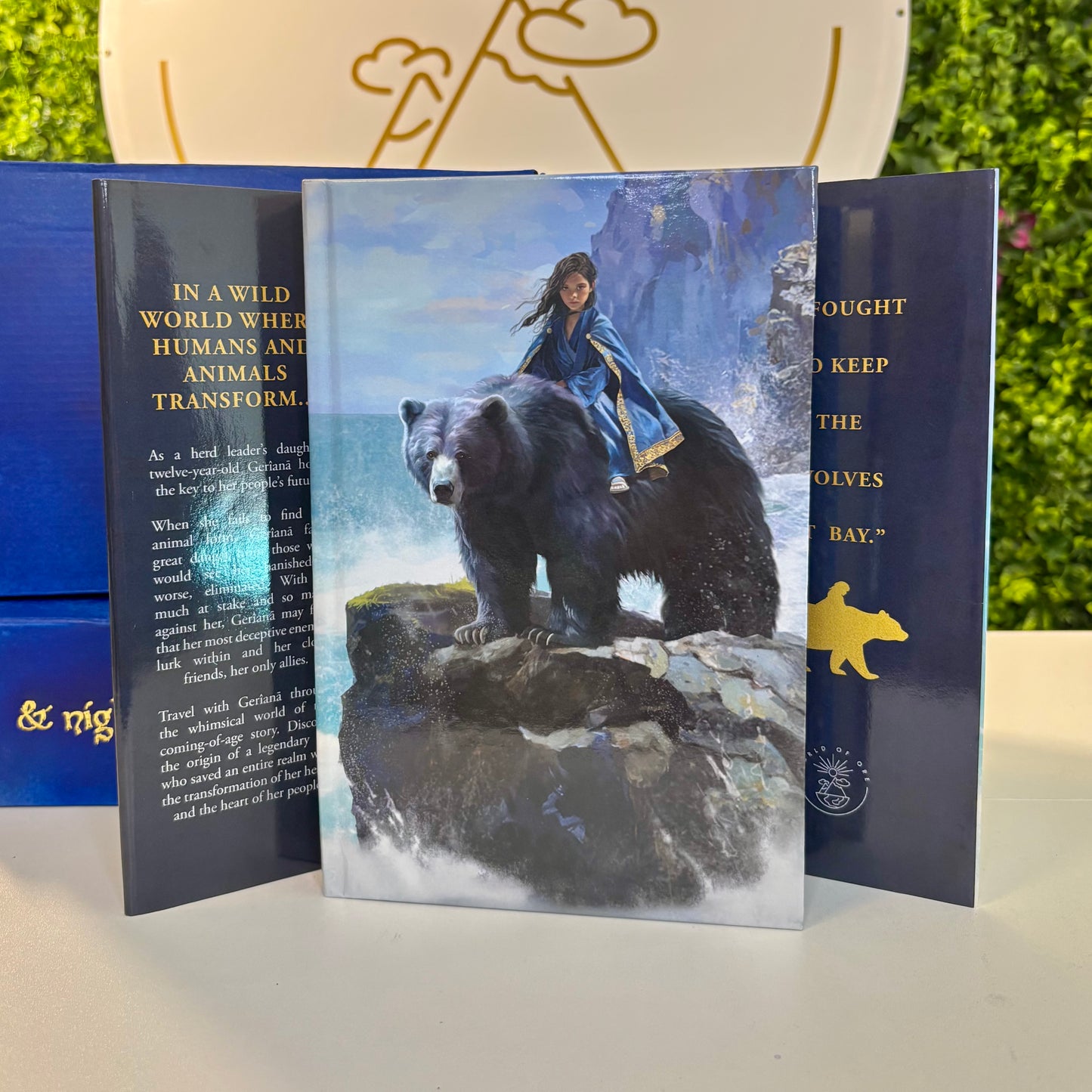 Book with a cover featuring a girl riding a bear, set against a scenic background.