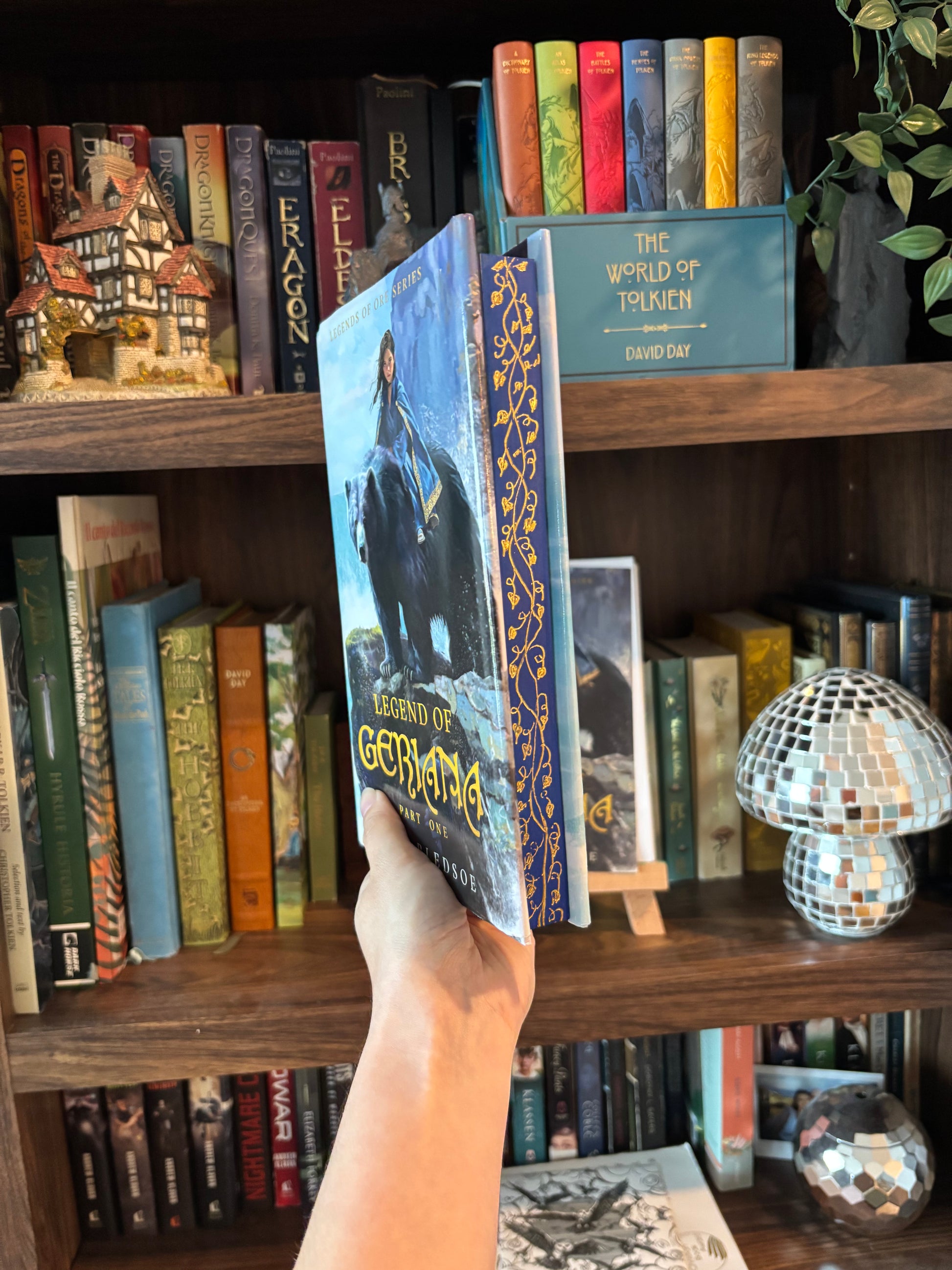 Hand selecting a book from a shelf filled with various books and decorative items.